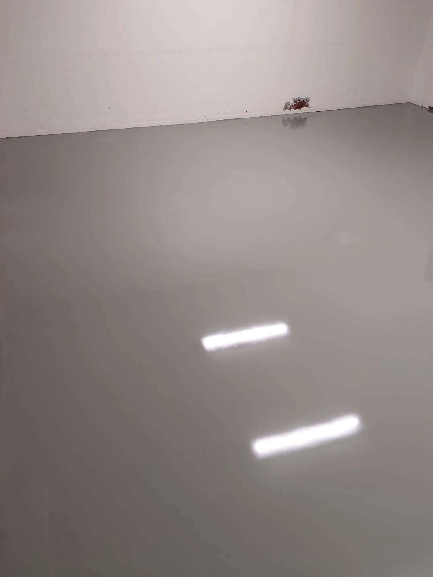 Glatte Bodenfläche mit Epoxidharzbeschichtung und Lichtreflexion im Innenraum