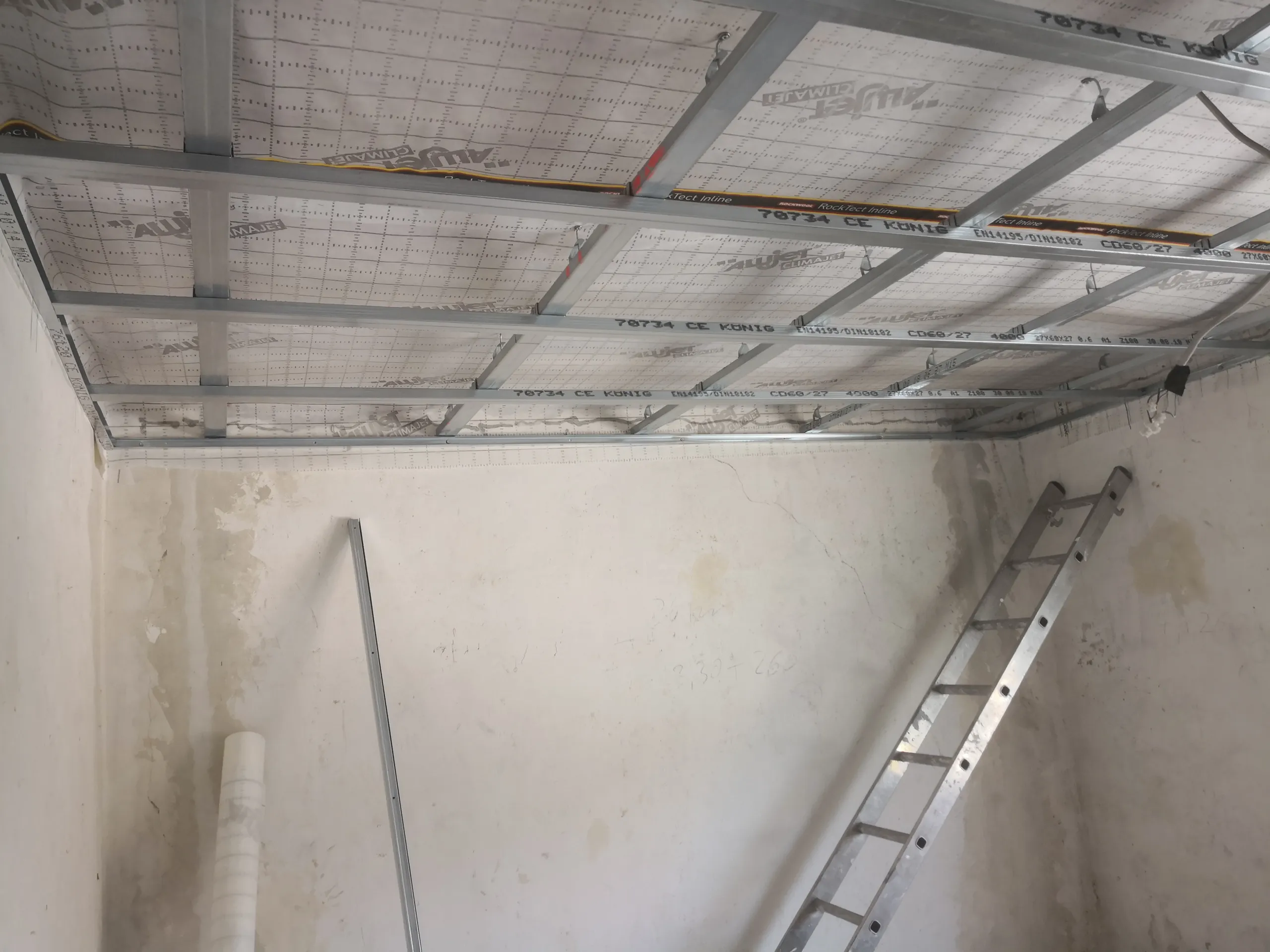 Metallunterkonstruktion und Dampfbremsfolie für abgehängte Trockenbaudecke in Rohbau mit Leiter