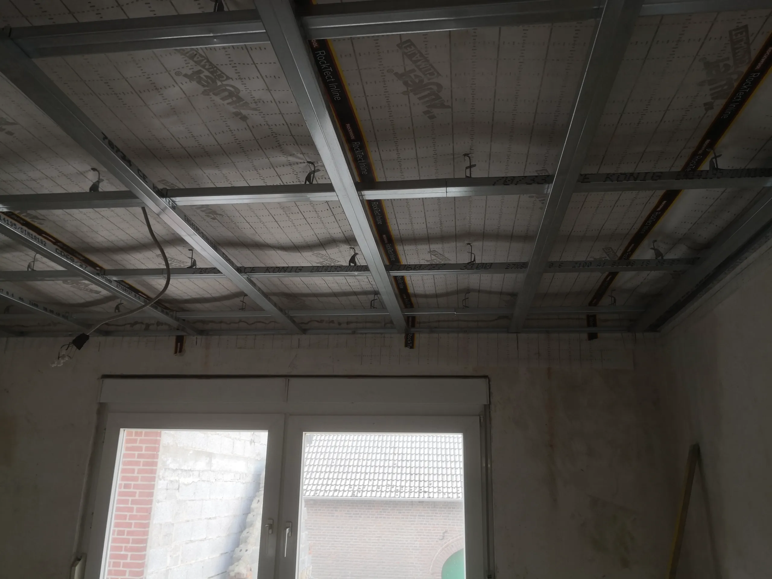 Unterkonstruktion aus Metallprofilen für Trockenbaudecke in einem Raum mit Fenster