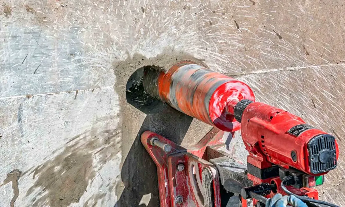 Rote Bohrmaschine bei Kernbohrarbeiten in Betonwand