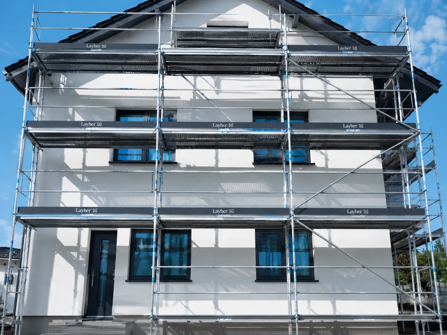 Weiß verputztes Einfamilienhaus mit mehrstöckigem Gerüst für Fassadensanierung
