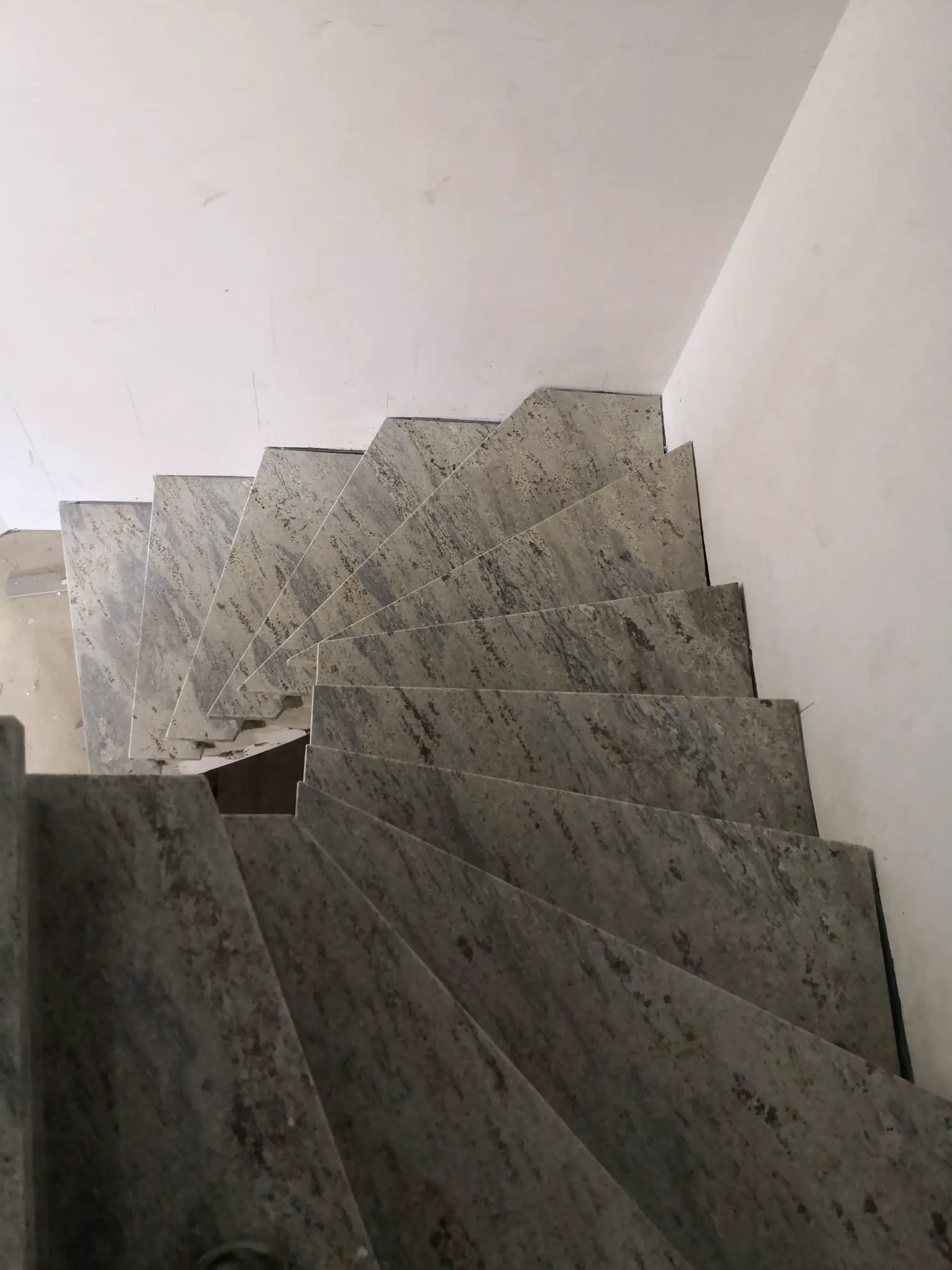 Eng gewendelte Treppe aus grauem Naturstein (Granit treppe) in Innenbereich mit Putzwänden