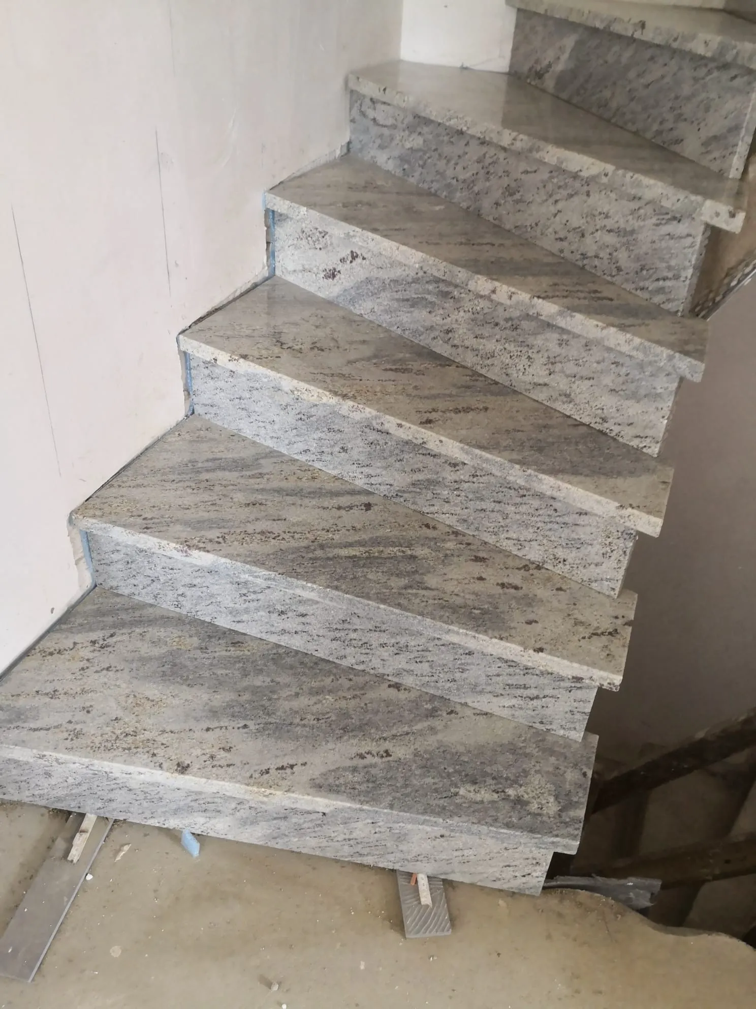 Neumontierte Granit treppe mit geschwungenem Verlauf und dreieckigen Stufen im Rohbau