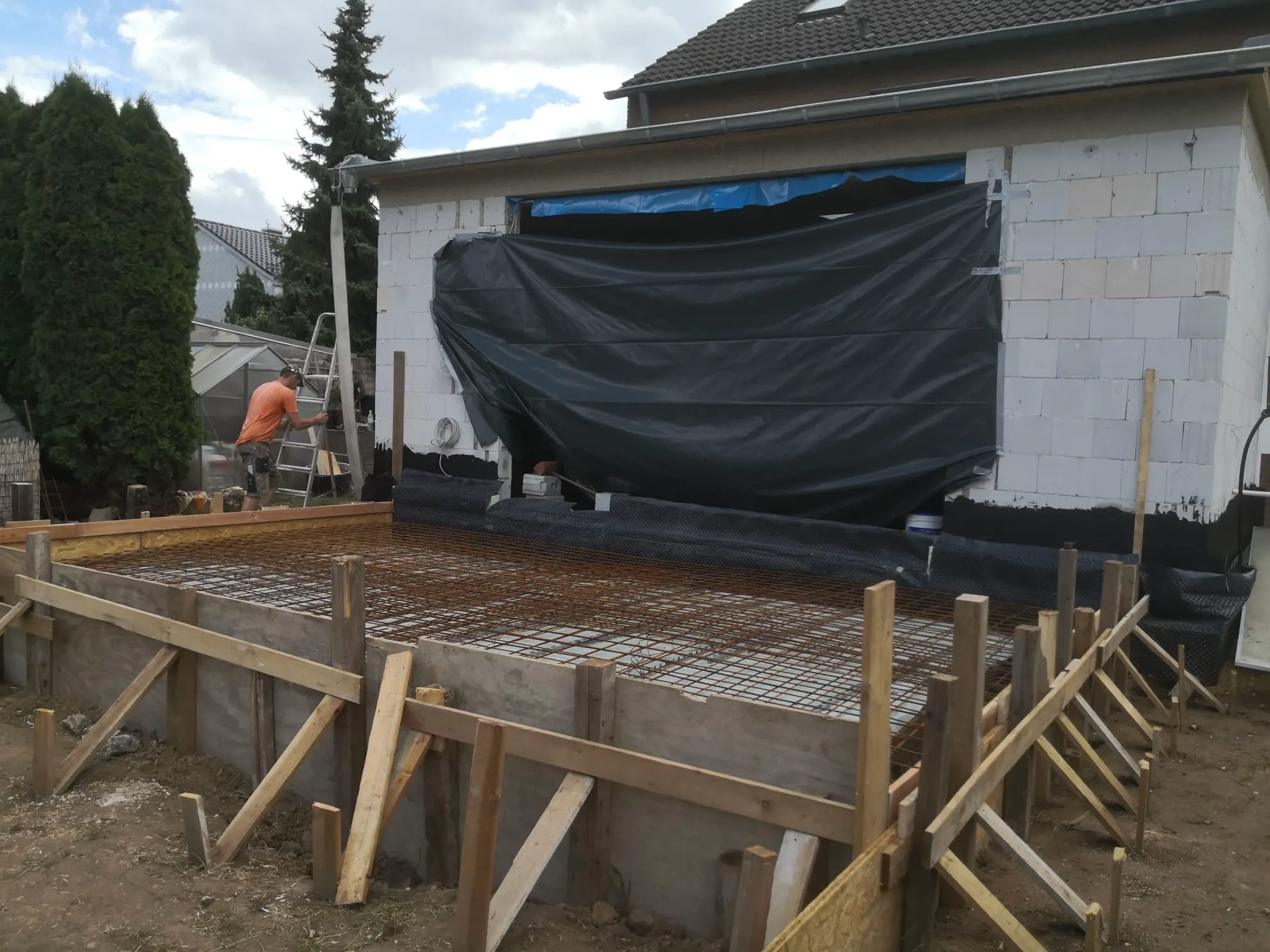 Fundament mit bewehrter Fundamentplatte, Holzverschalung und Schalung vor Rohbauwand