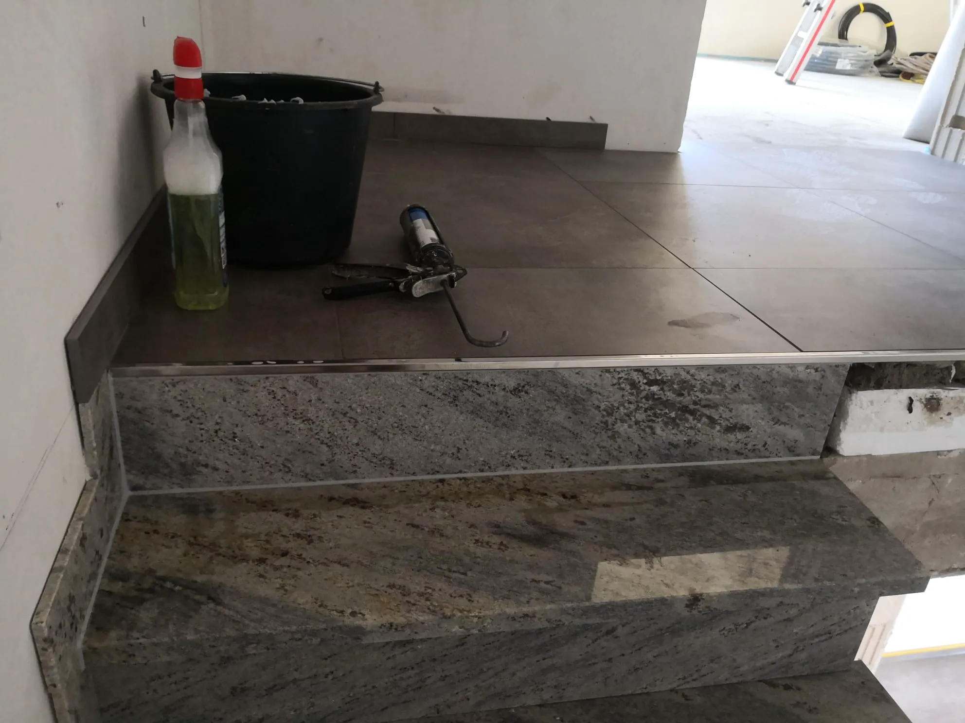 Granit treppe mit gefliester Podeststufe, Silikonpistole und Montageeimer