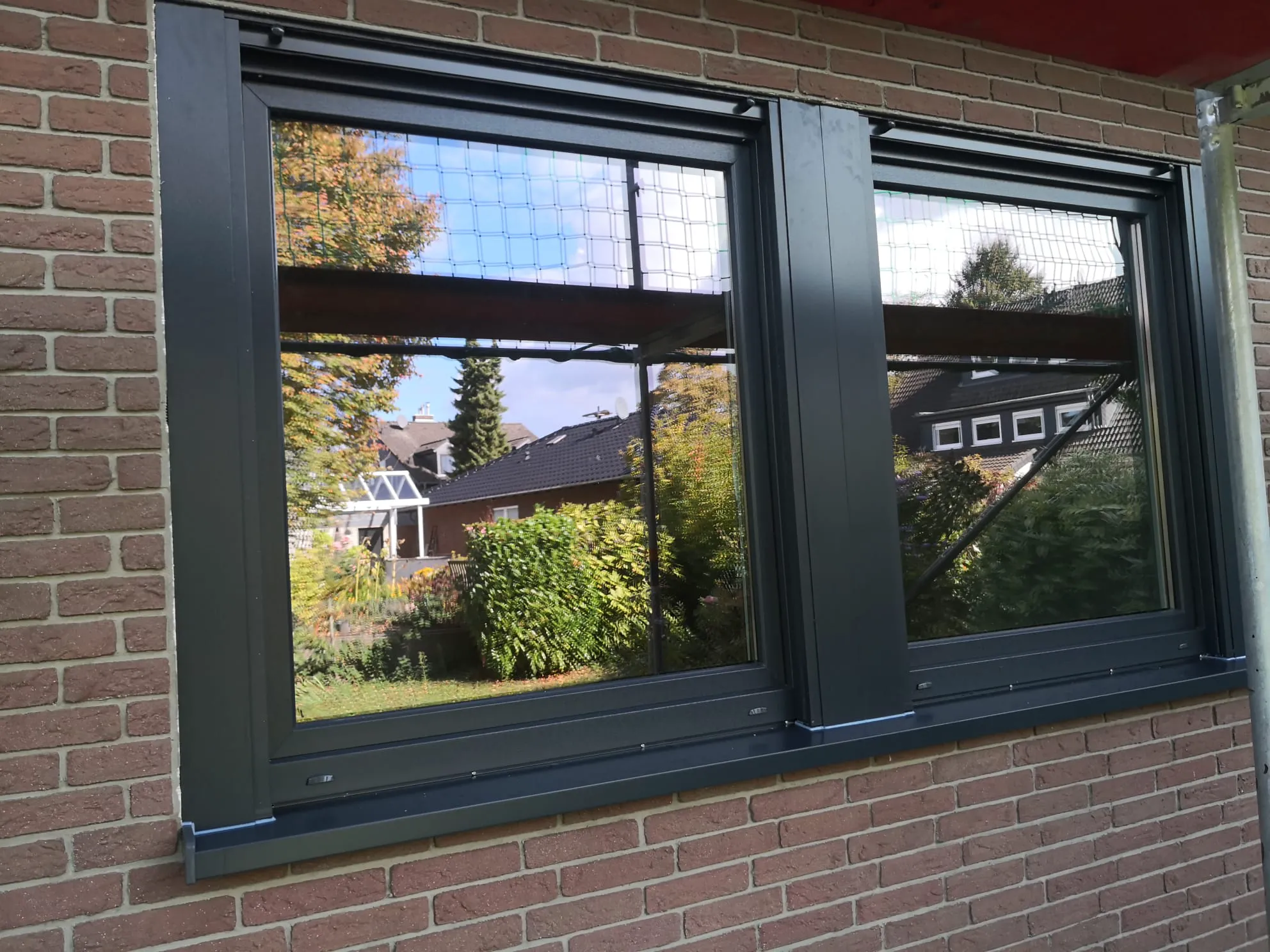 Zwei Fenster mit anthrazitfarbenen Rahmen in roter Klinkerfassade