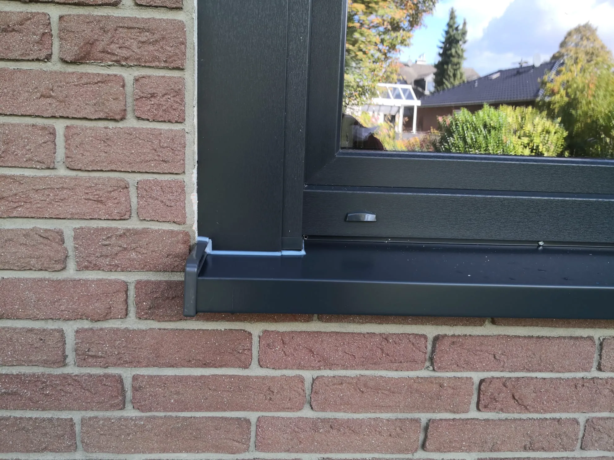 Schwarzer Fenstersims und Fensterrahmen in einer roten Klinkerwand