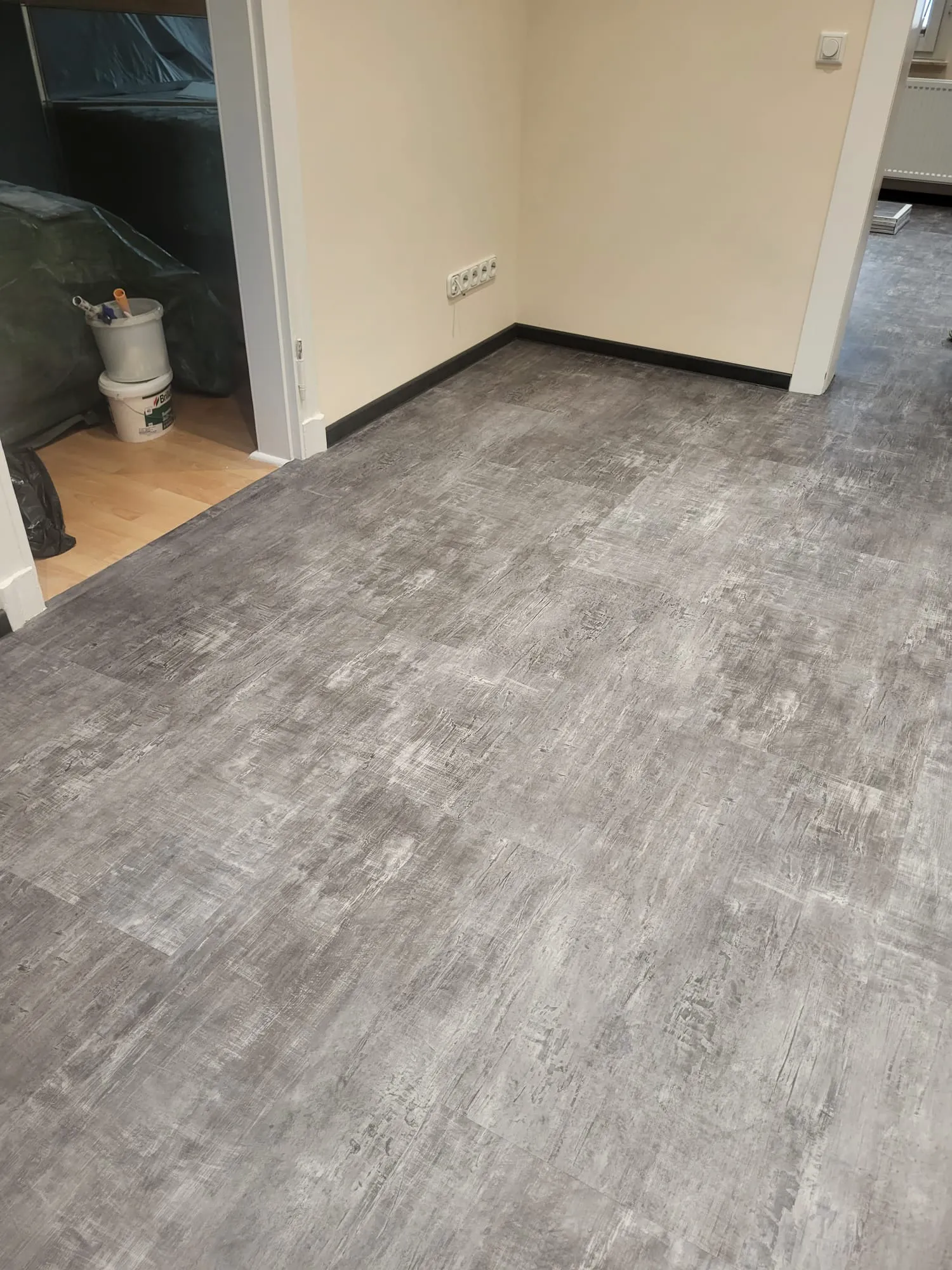 Neu verlegter grauer Vinylboden in Innenraum mit Tür- und Wandabschlüssen, Beispiel für Vinylboden verlegen