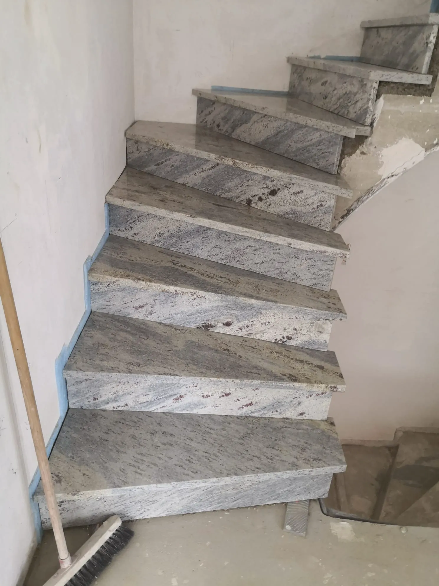 Graue Granit treppe mit gewendelten Stufen in unfertigem Treppenhaus, präzise verlegt