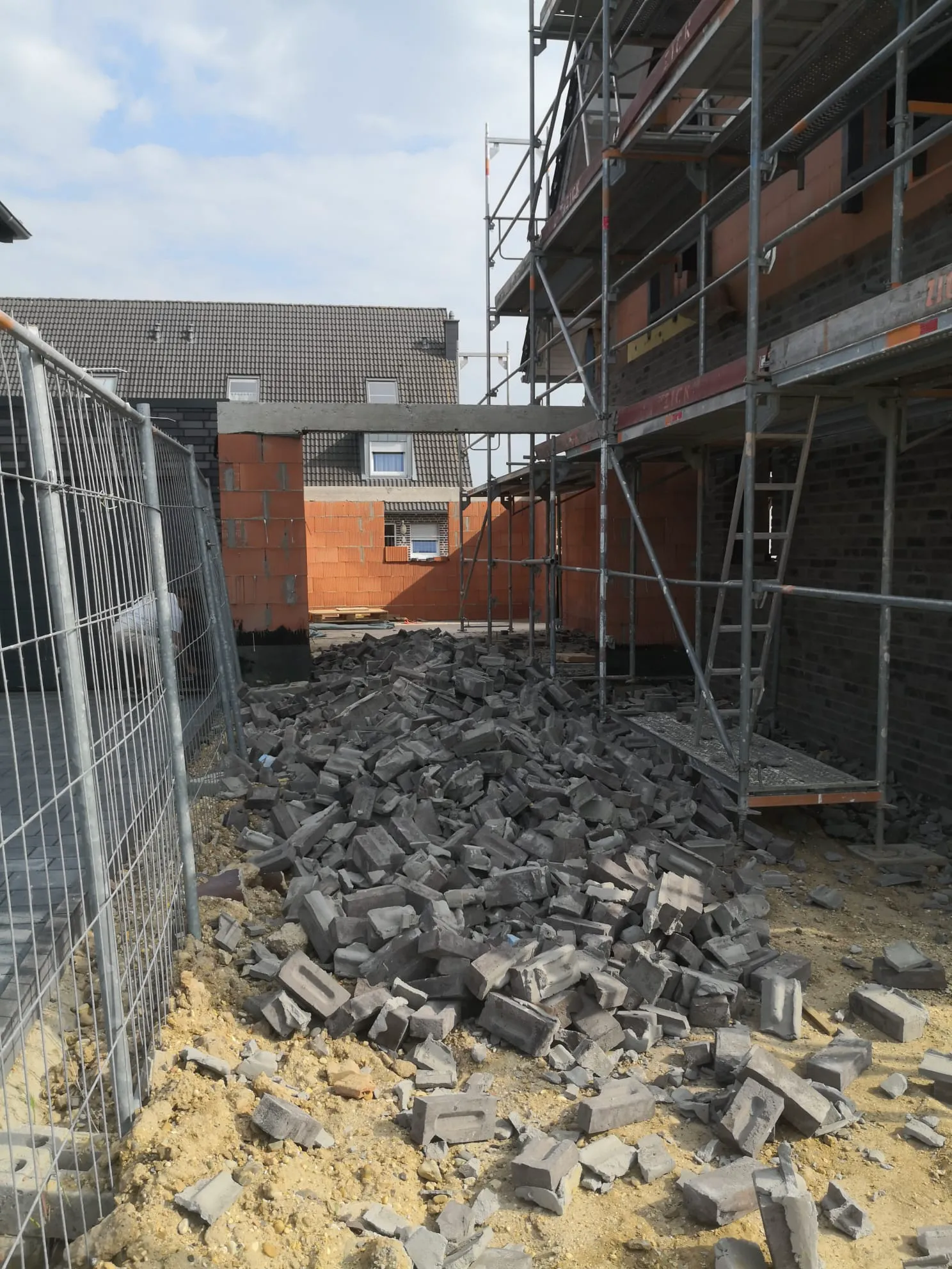 Gerüst vor Rohbau mit Ziegeltrümmern bei Abbrucharbeiten