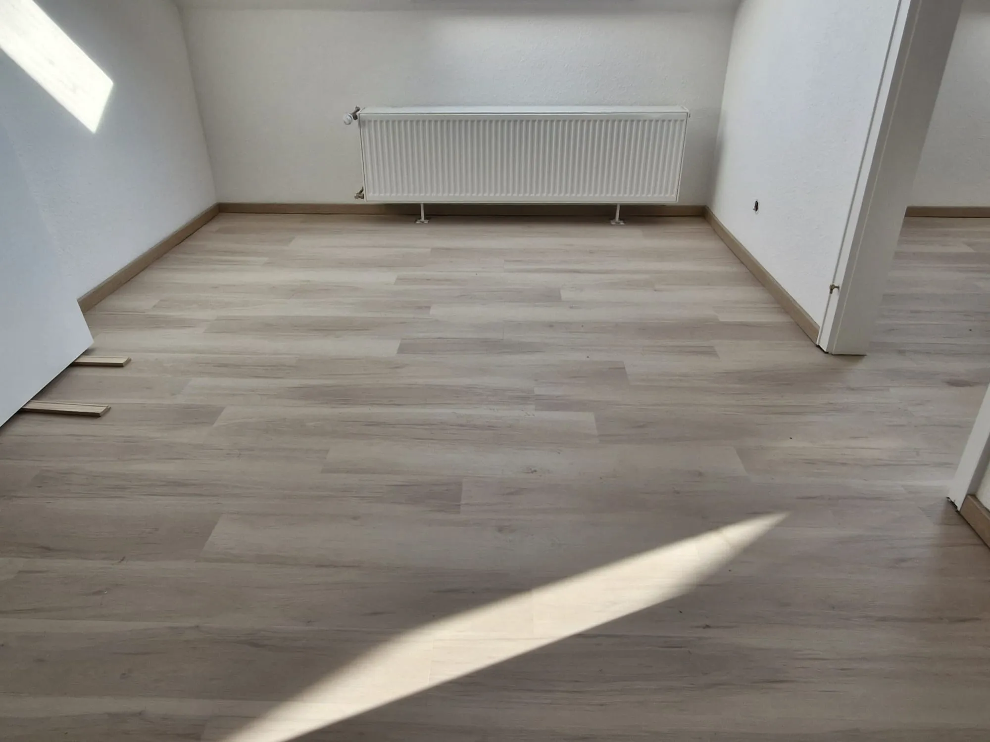 Neu verlegter Laminatboden mit Sockelleisten in hellem Raum – Laminat verlegen