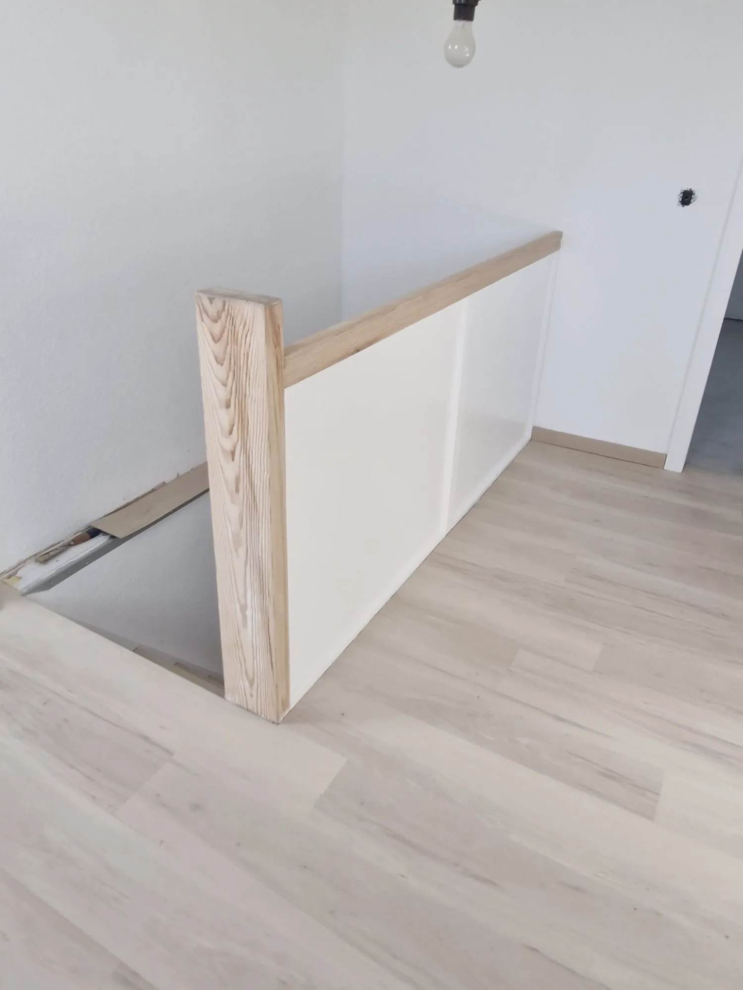 Offene Treppenbrüstung mit naturbelassenem Holzgeländer und klar weiß verputzter Wand