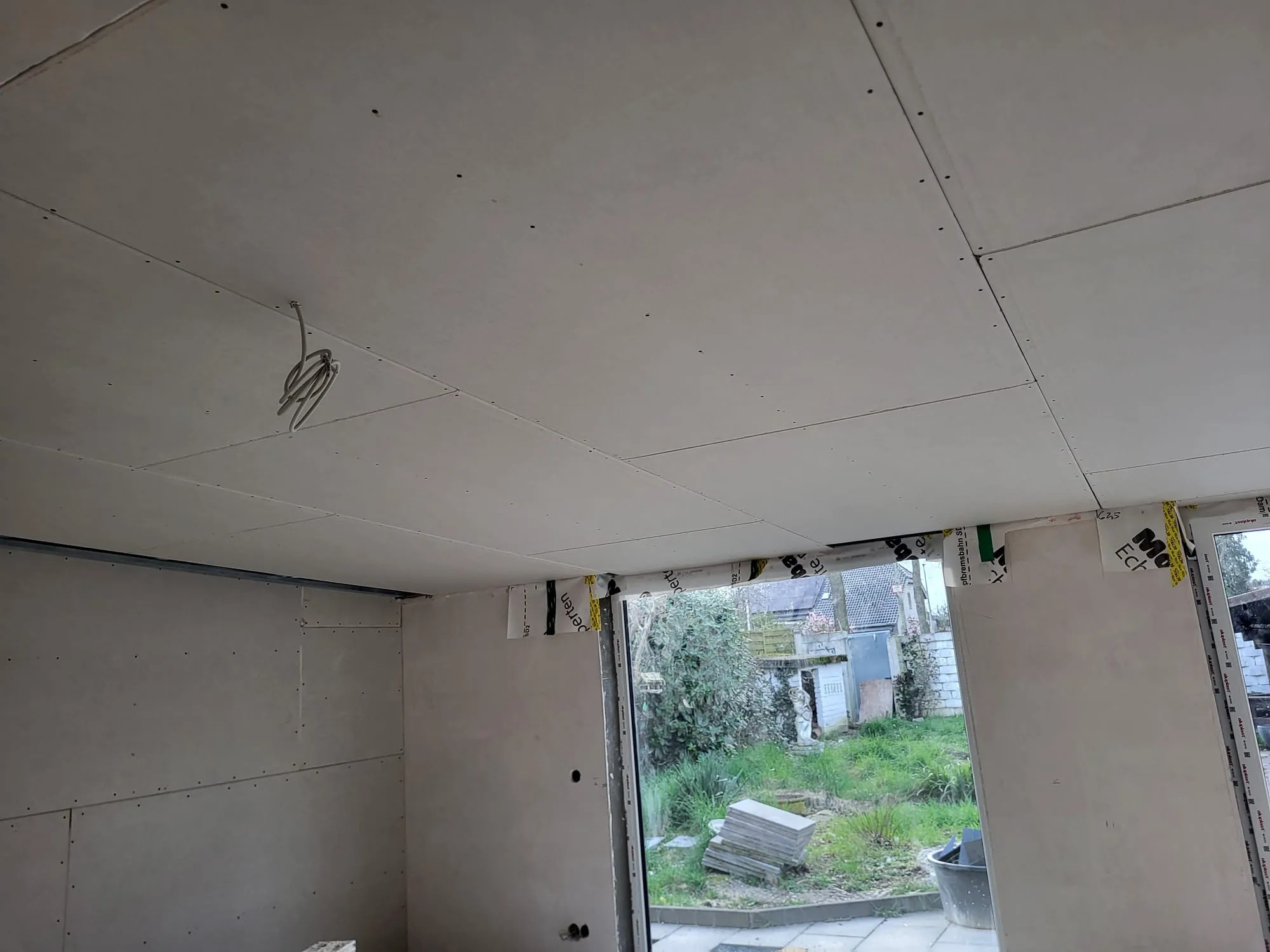 Trockenbau mit Gipskartonplatten an Decke und Wänden, sichtbare Schrauben und Elektrokabel
