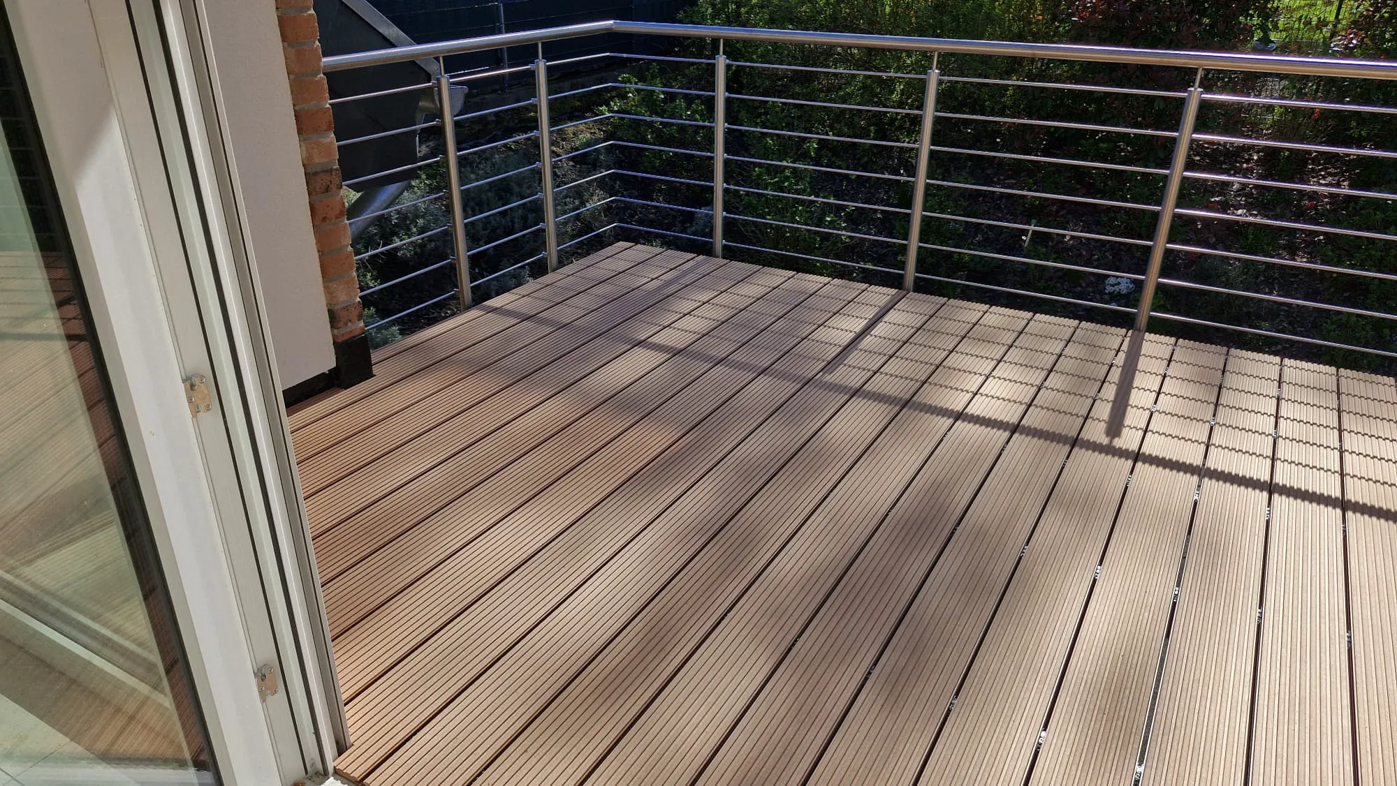 Balkonterrasse aus Holzterrassendielen mit Metallgeländer – Terrassenbau