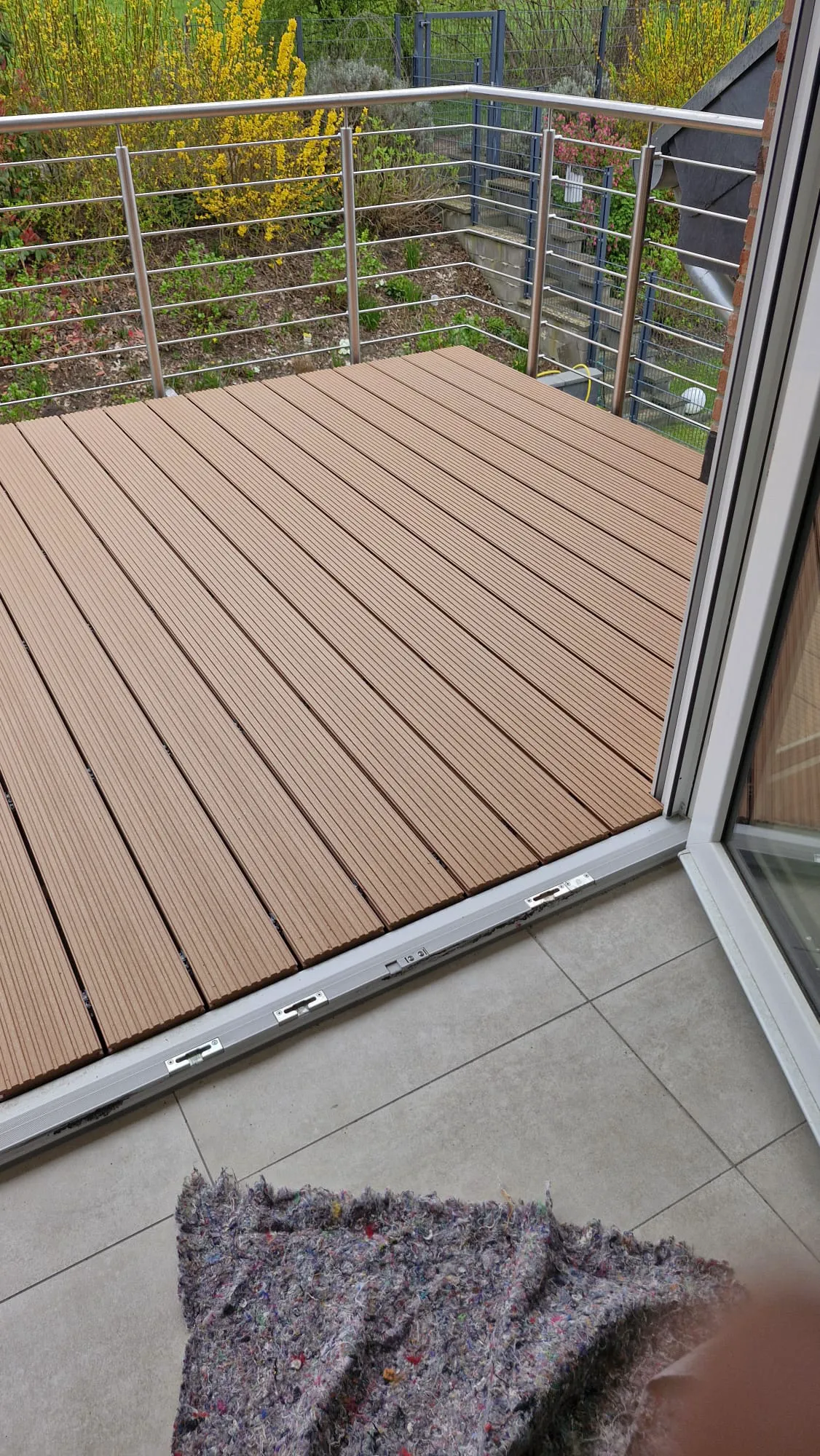 Terrassenbau mit braunen Holz-Dielen und Metallgeländer, Blick vom Innenraum über die Terrassenschwelle