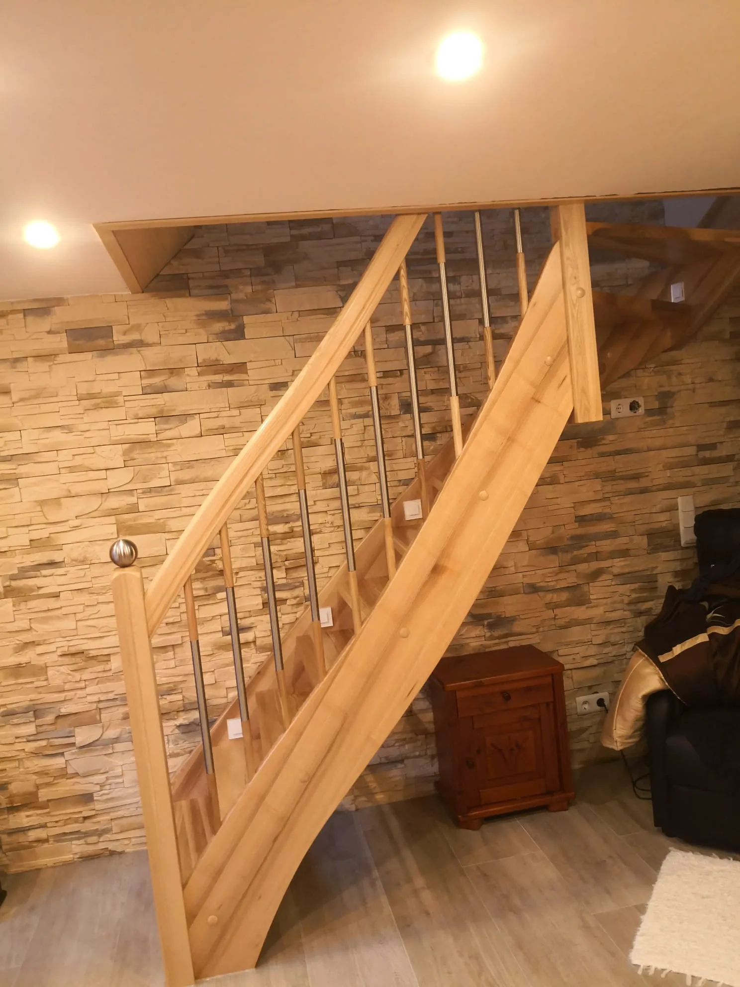 Moderne Holztreppe mit Metallgeländer vor Steinverblender-Wand im Wohnbereich