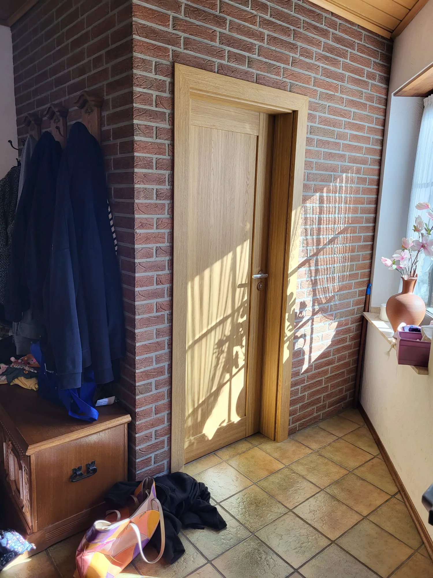 Innentüren im hellen Flur mit Klinkerriemchenwand, Garderobe und Fliesenboden